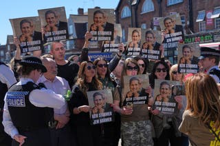 Protesters hold posters near the scene where two people were stabbed yesterday